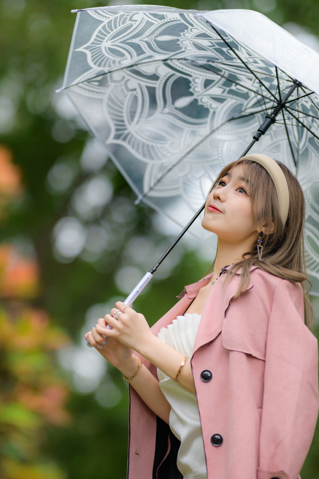 Девушка азиатка в пальто под прозрачным зонтом