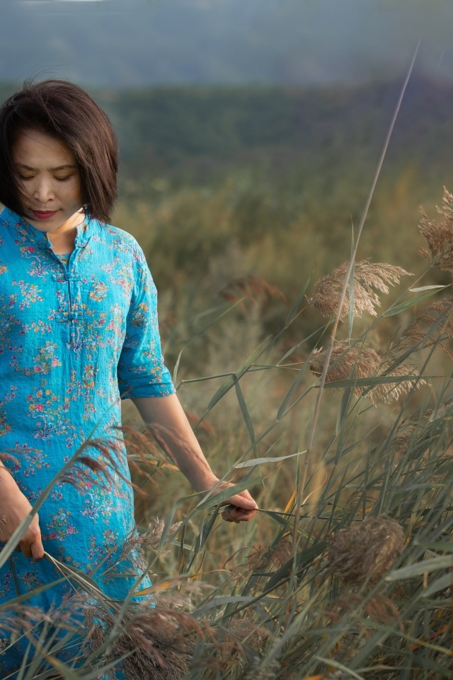 Девушка азиатка в платье на поле с колосьями