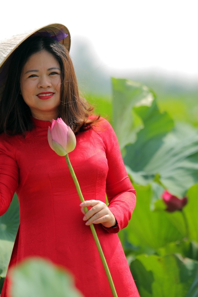 Девушка азиатка в красном платье у цветов лотоса