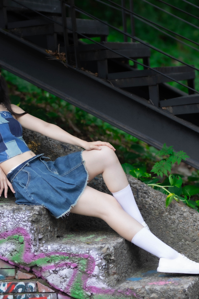 Девушка азиатка в юбке лежит на лестнице