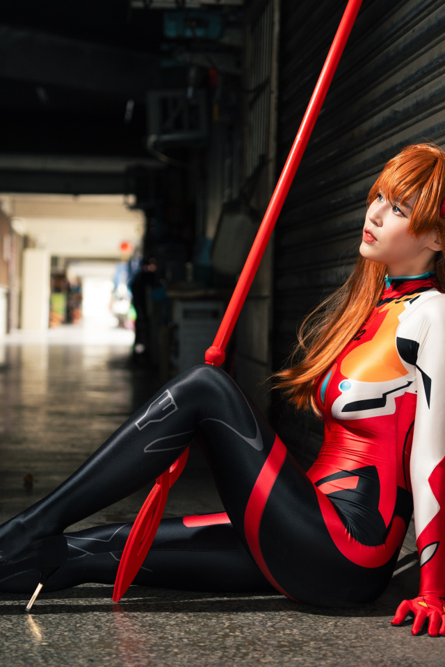 Девушка азиатка в костюме сидит у стены