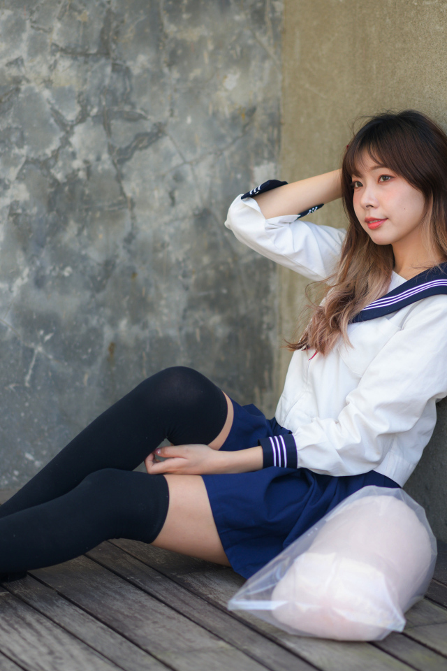 Азиатка в черных чулках сидит у стены