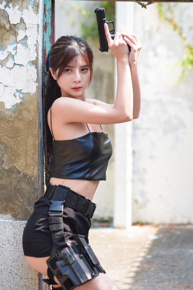 Девушка азиатка с пистолетом в кожаном костюме