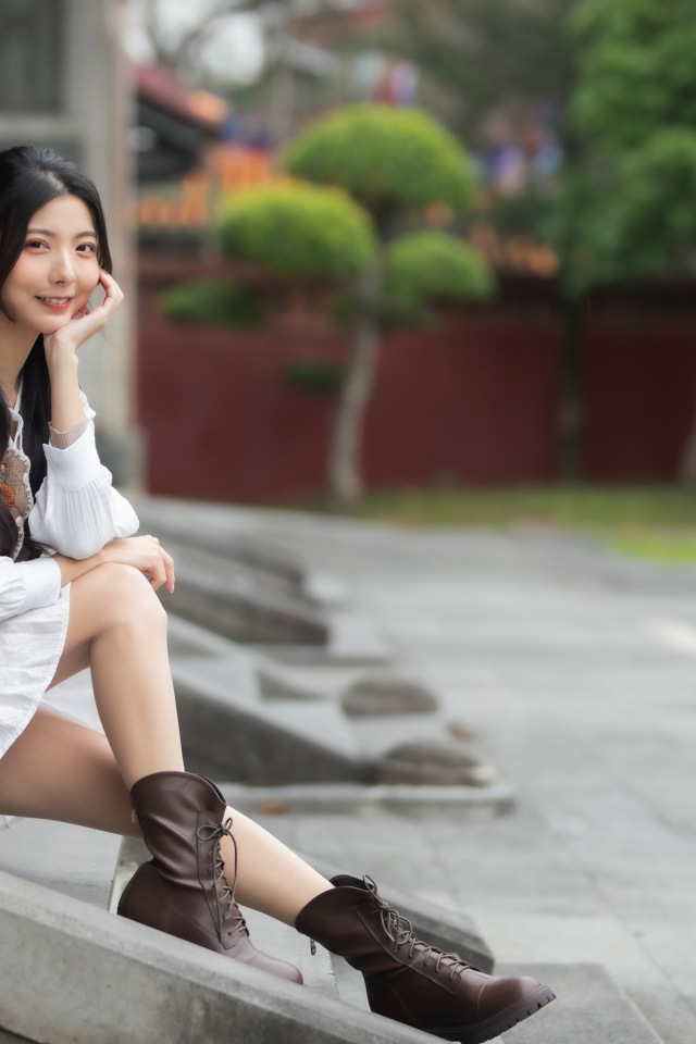 Азиатка сидит на холодных ступеньках