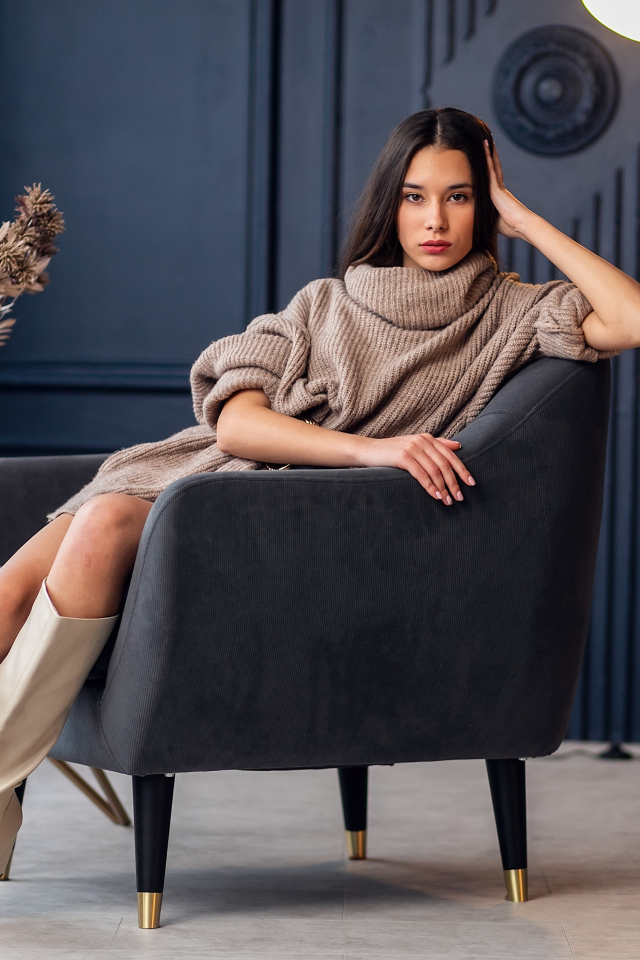 Красивая брюнетка в сапогах сидит в кресле