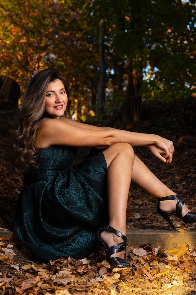 Красивая девушка в платье сидит на земле в осеннем парке