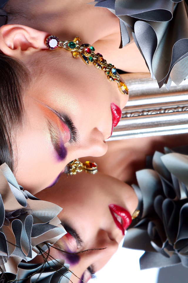 Красивая девушка с ярким макияжем отражается в зеркале