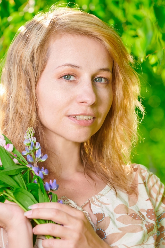 Красивая девушка с цветами люпина в руке