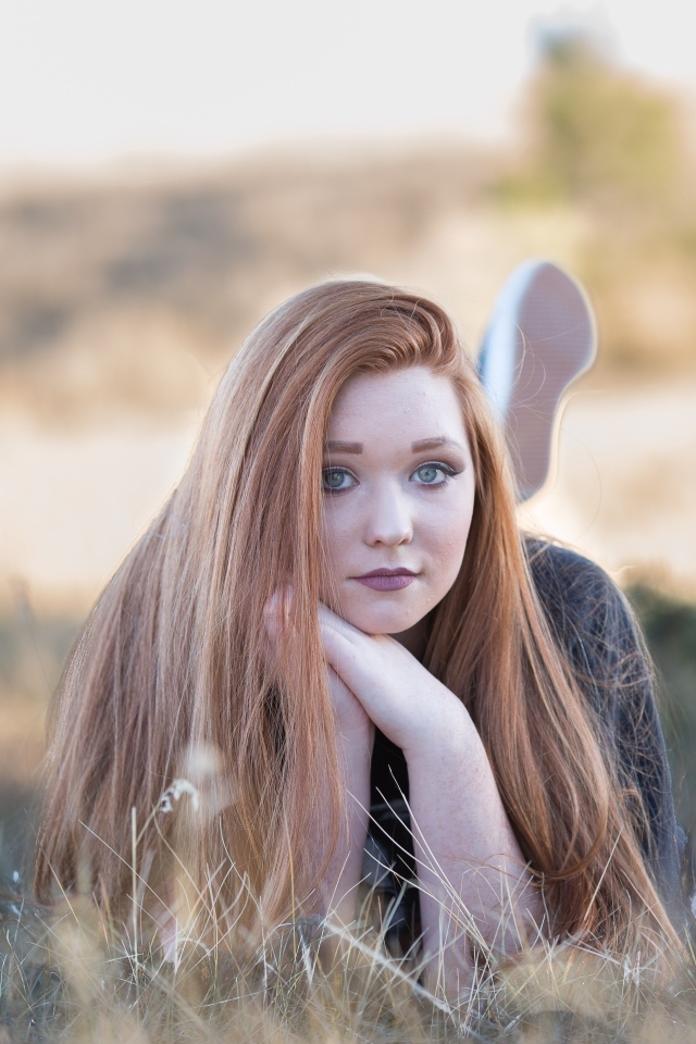 Красивая рыжеволосая девушка лежит на траве