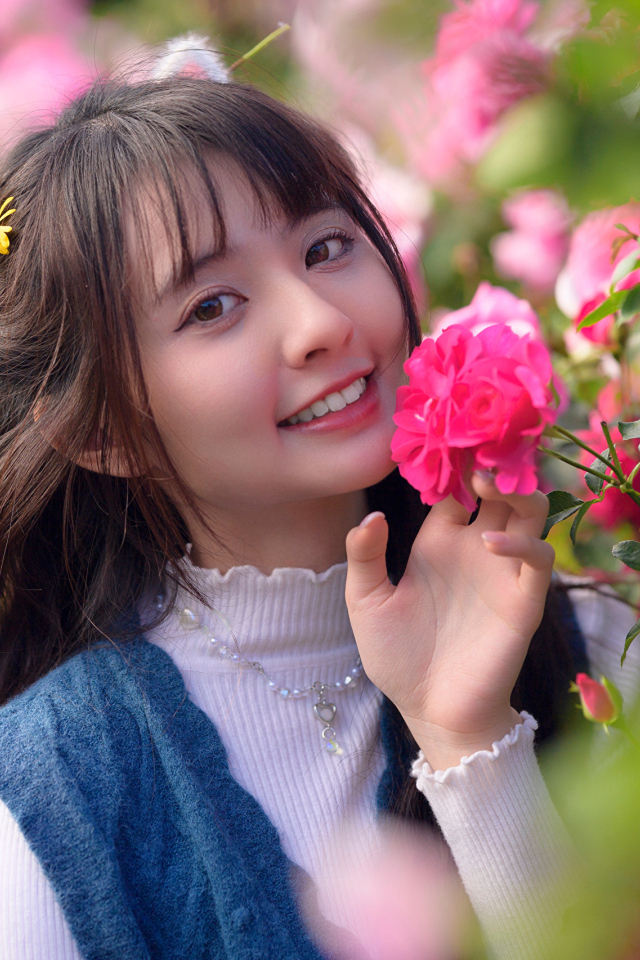 Красивая улыбающаяся азиатка с розовым цветком розы