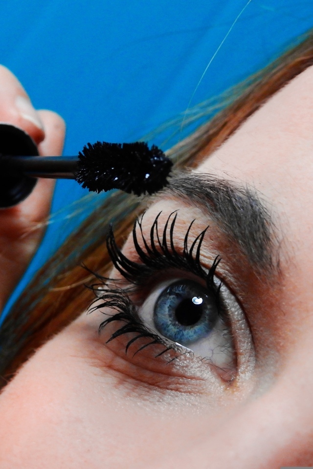 Голубоглазая девушка красит ресницы тушью