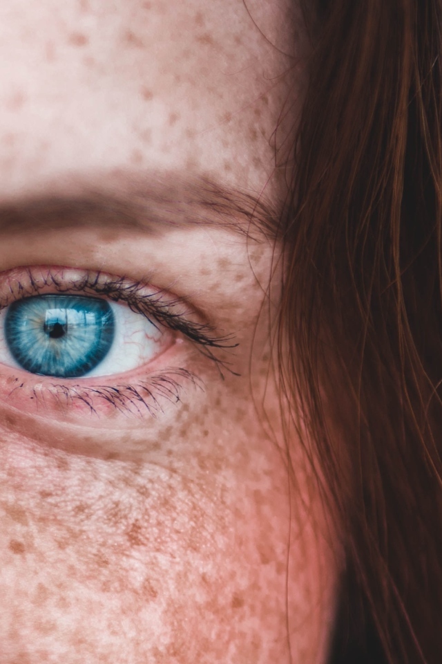 Голубой глаз рыжеволосой девушки с веснушками