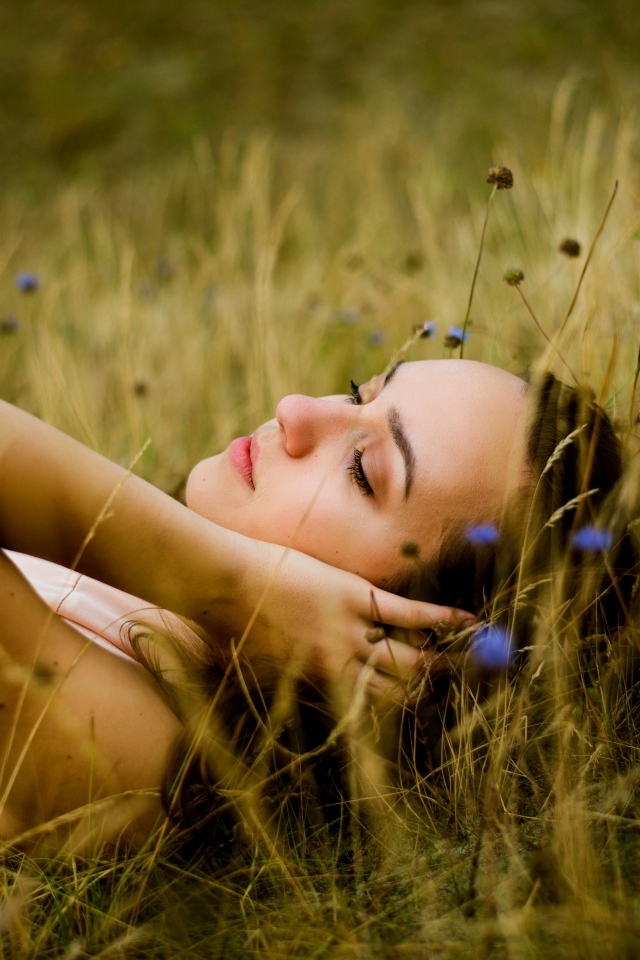 Милая девушка лежит на траве на поле