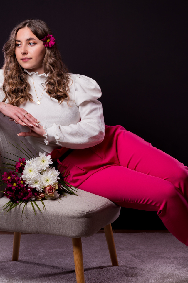 Милая девушка сидит на сером кресле с цветами