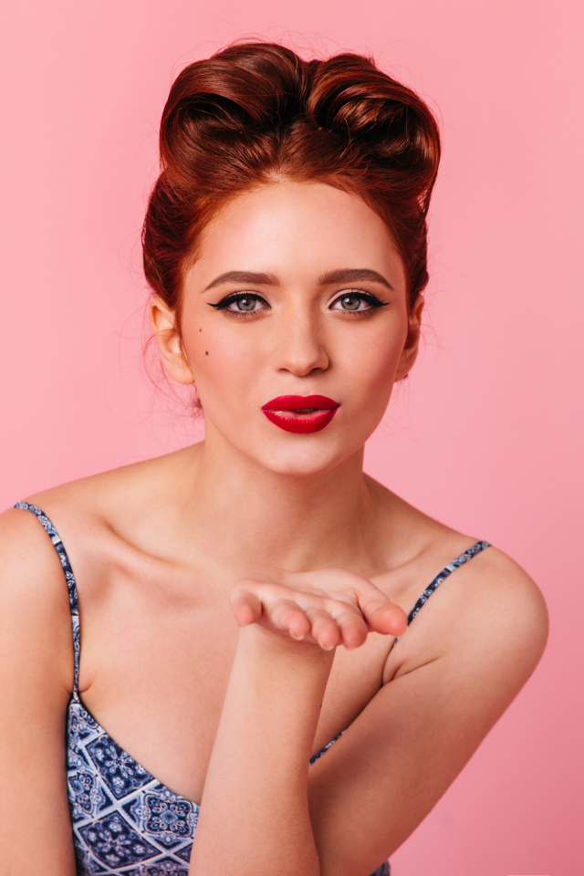 Милая рыжеволосая девушка на розовом фоне