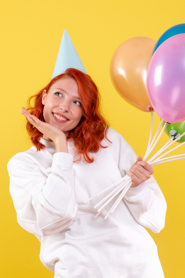 Милая рыжеволосая девушка с шариками на желтом фоне