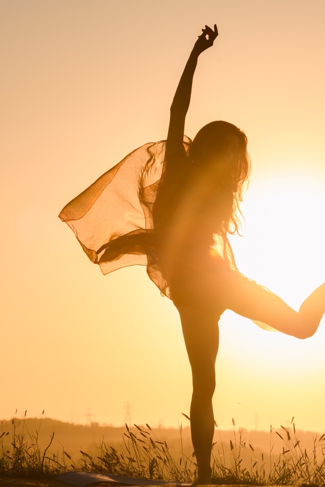 Девушка танцует в лучах солнца на закате