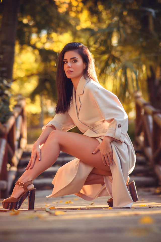 Девушка в пальто на мосту в парке 