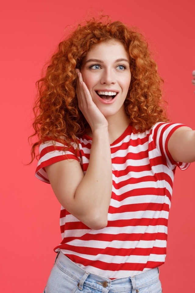 Девушка делает селфи на красном фоне