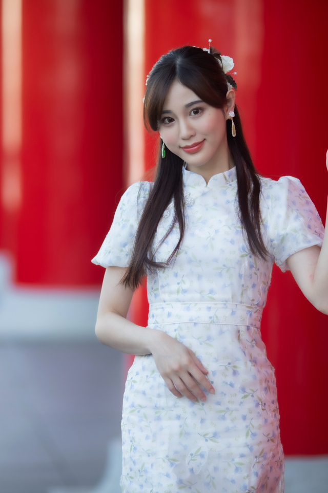 Длинноволосая азиатка позирует у красной колонны