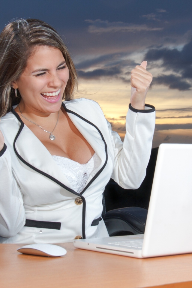 Довольная женщина с карточкой за столом с ноутбуком