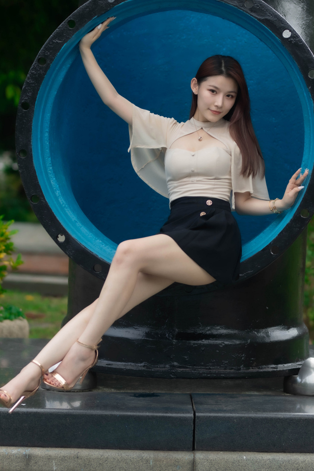 Стройная длинноногая азиатка сидит в трубе