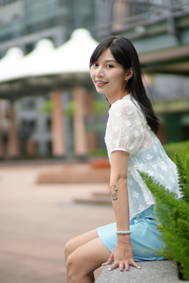 Улыбающаяся азиатка в белой блузке у дома