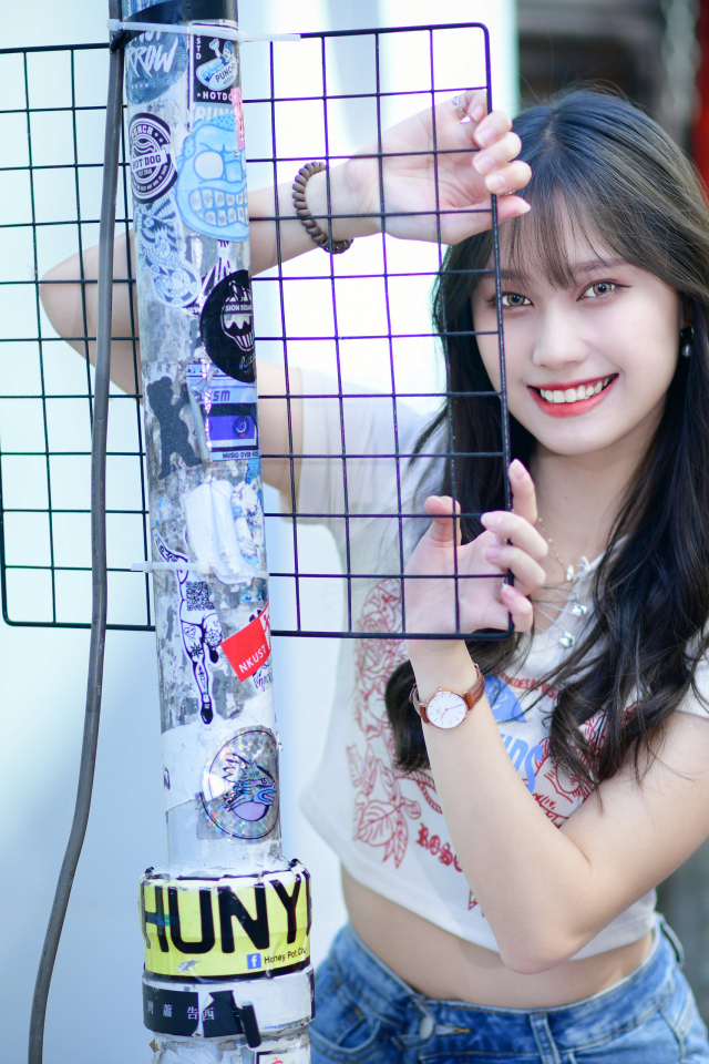 Улыбающаяся азиатка держится за сетку