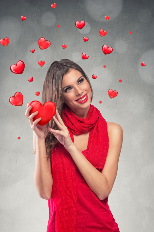 Улыбающаяся девушка в красном платье с сердечками на сером фоне
