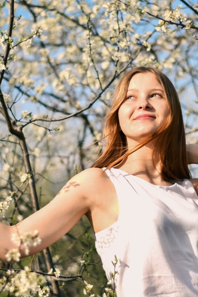Молодая девушка у цветущего дерева весной