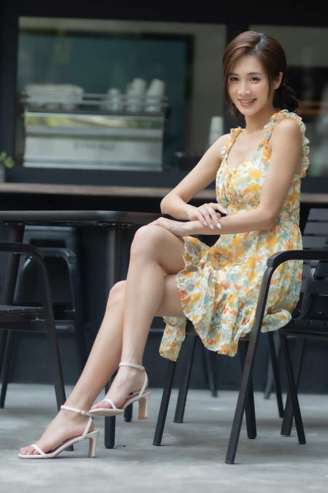 Молодая улыбающаяся азиатка за столиком в кафе