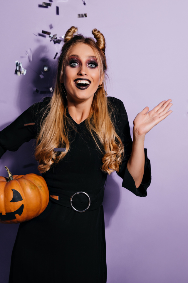 Девушка в черном костюме с тыквой на праздник Хэллоуин