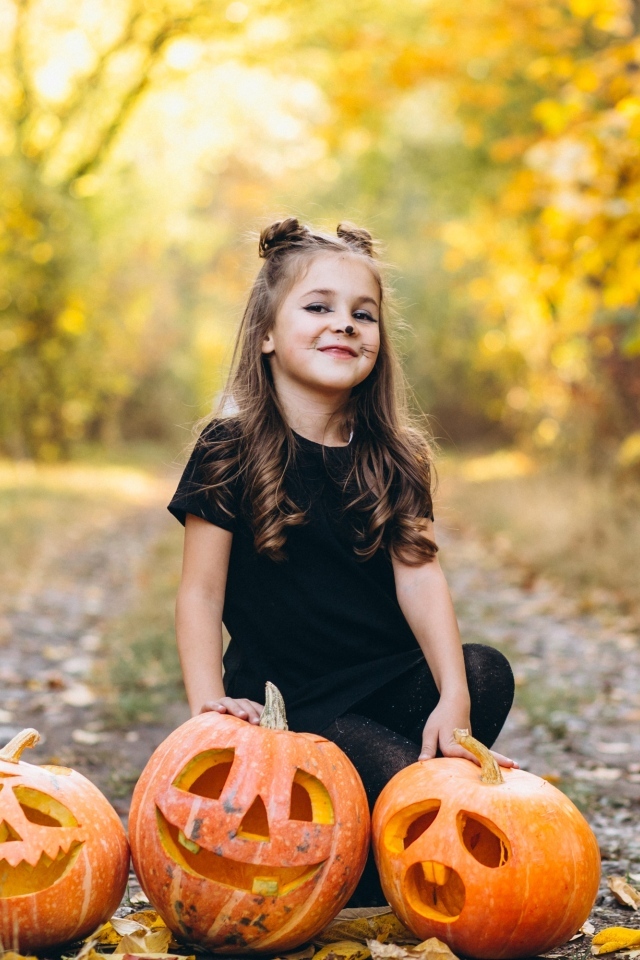 Девочка с тыквой в парке на праздник Хэллоуин