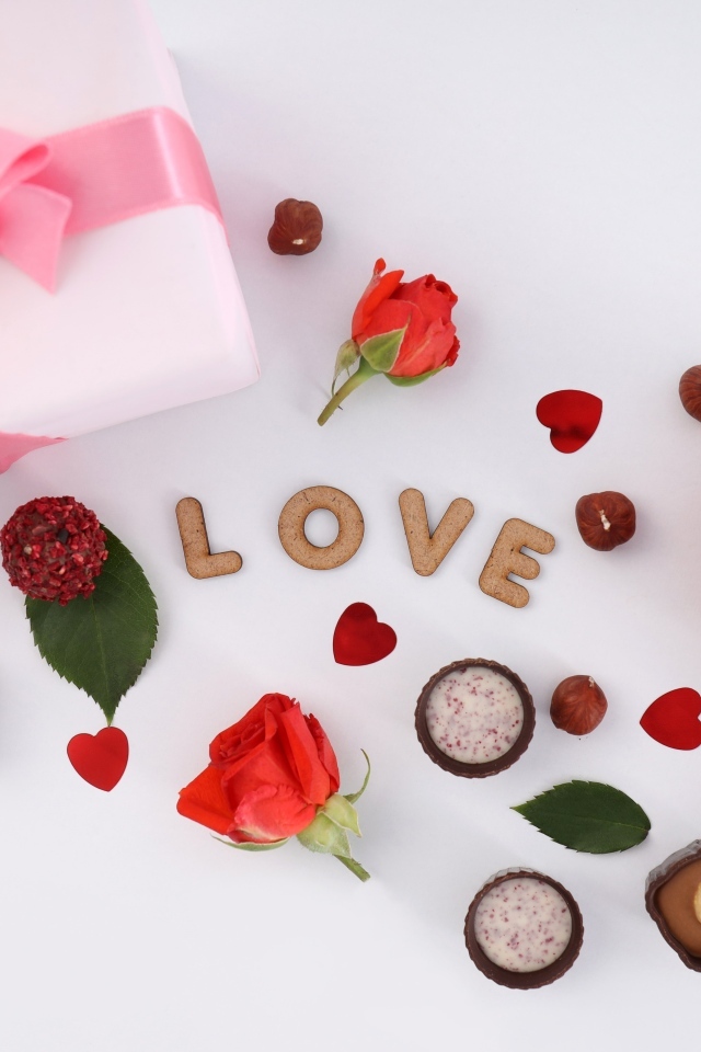 Подарок и сердечки с конфетами на столе на День Святого Валентина