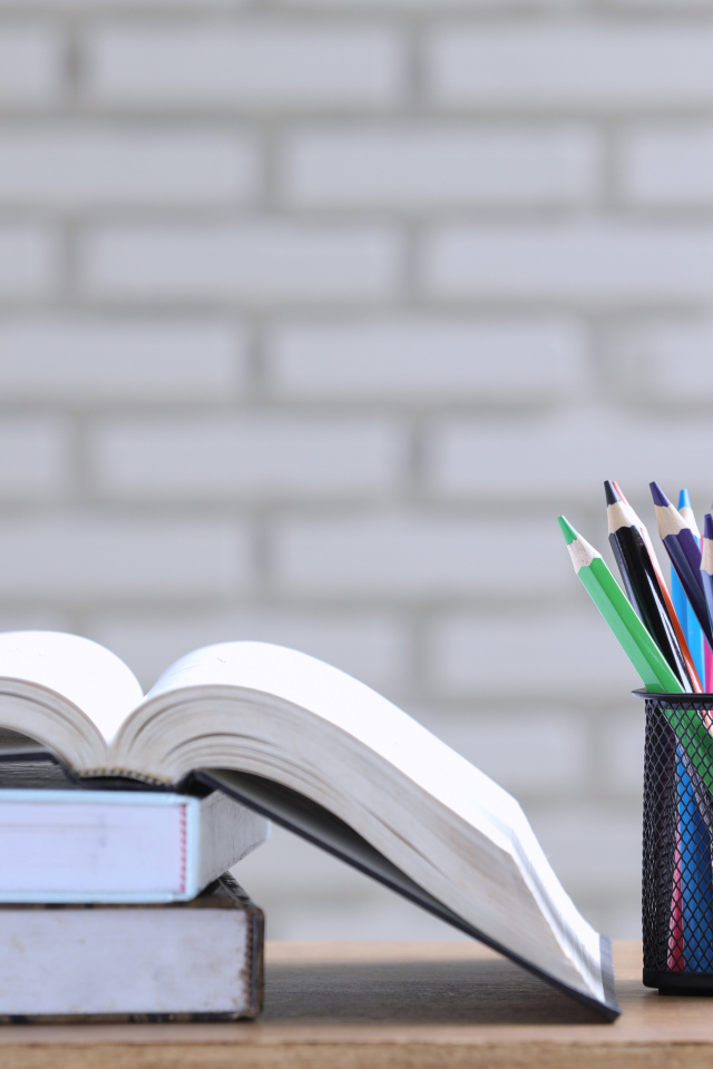 Разноцветные карандаши на столе с книгами 