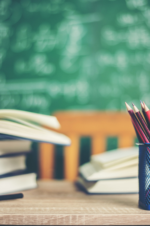 Карандаши на столе с книгами в школьном классе