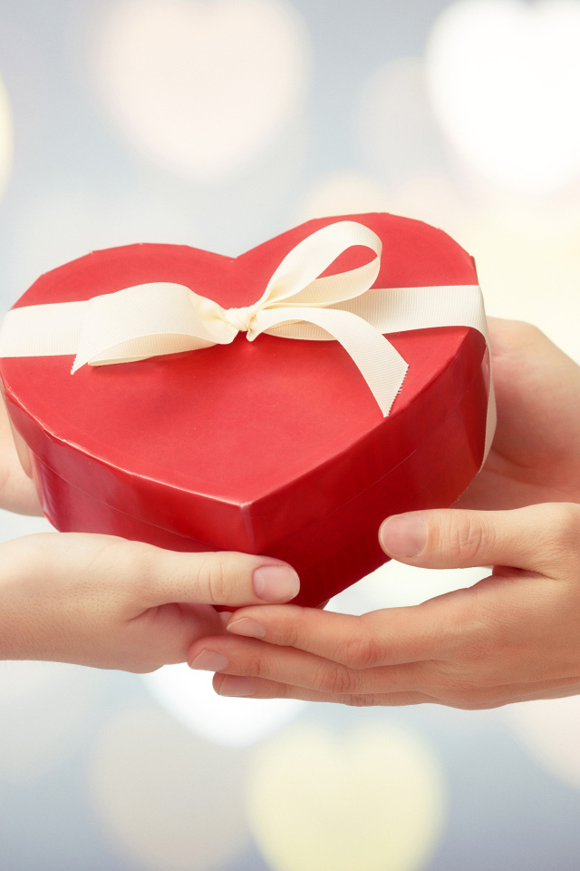 Коробка в форме сердца в руках у пары