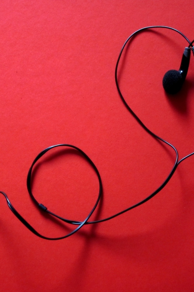 Черные наушники в форме сердца на красном фоне