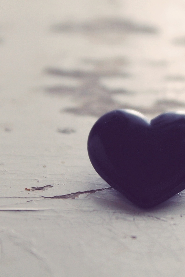 Черное каменное сердце на деревянной поверхности 