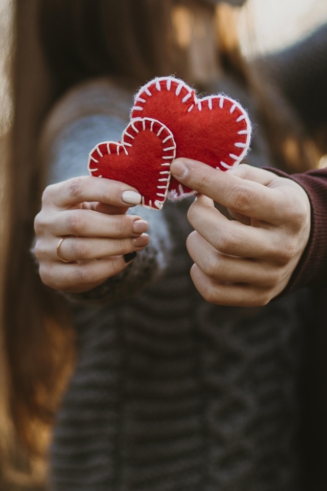 Влюбленная пара держит сердечки в руках