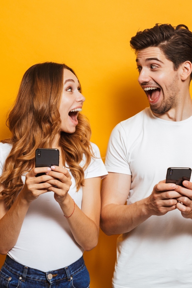 Счастливые парень и девушка с мобильными телефонами