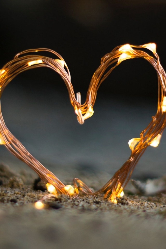 Сердце из гирлянды на песке