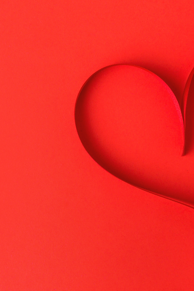 Сердце из атласной ленты на красном фоне