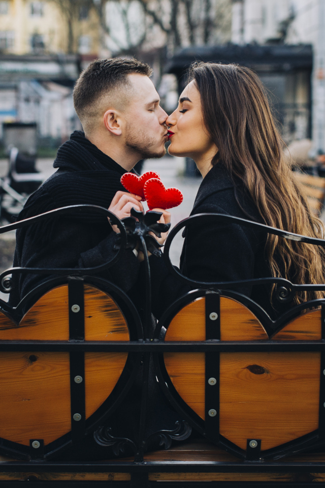 Поцелуй влюбленной пары на лавке в парке