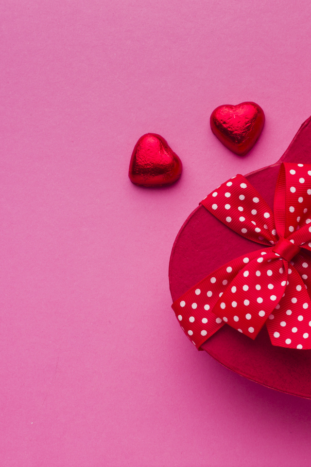 Большая красная коробка в форме сердца на розовом фоне