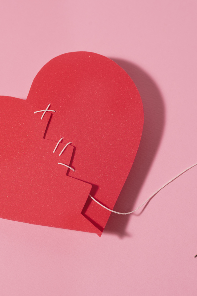 Бумажное сердце сшили нитками на розовом фоне