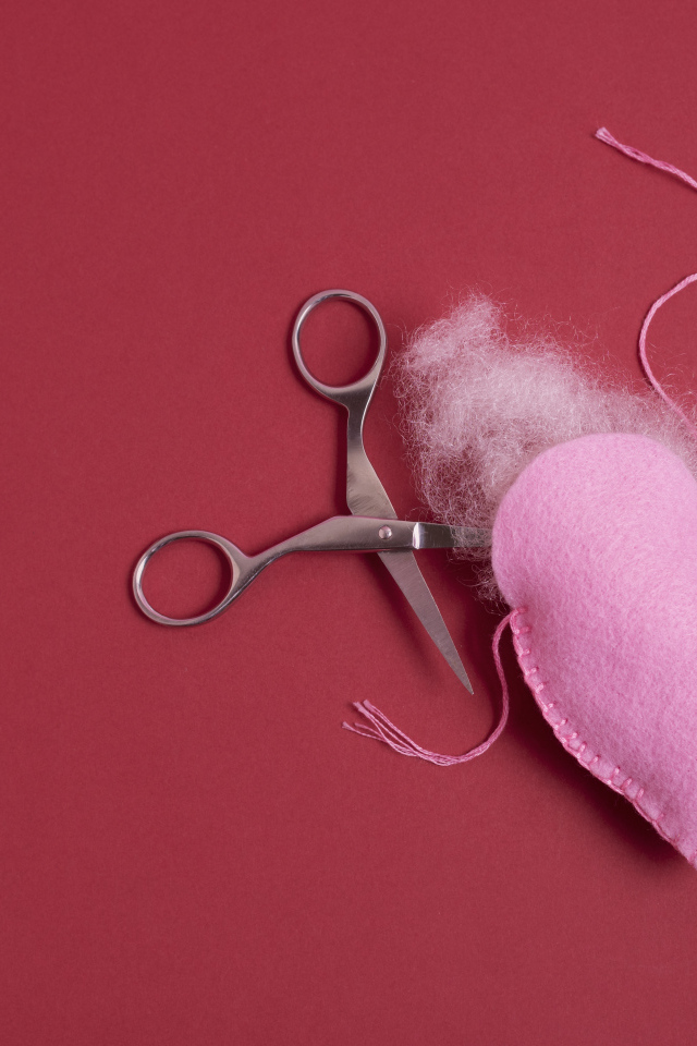 Розовое  сердце с ножницами на красном фоне