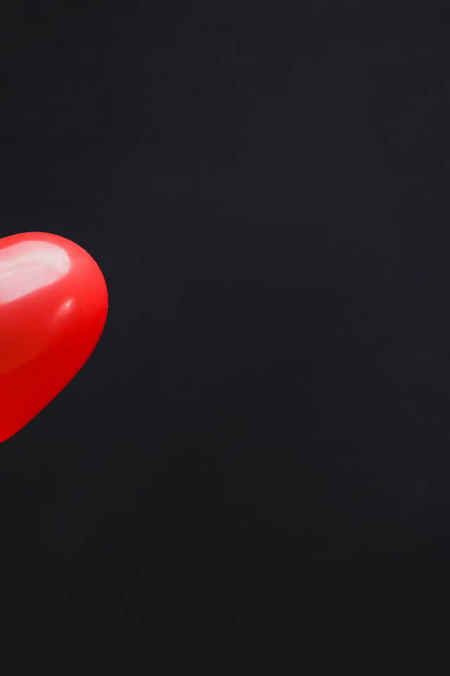 Красный шарик в форме сердца на черном фоне