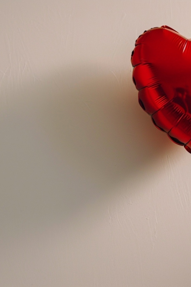 Красный шарик в форме сердца на сером фоне