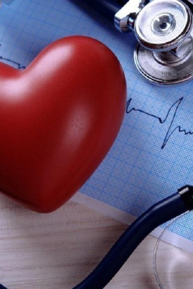 Красное сердце на столе с кардиограммой и стетоскопом
